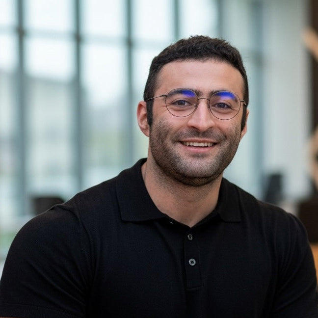 Tan Mazrouee wearing glasses and a black shirt in an office.